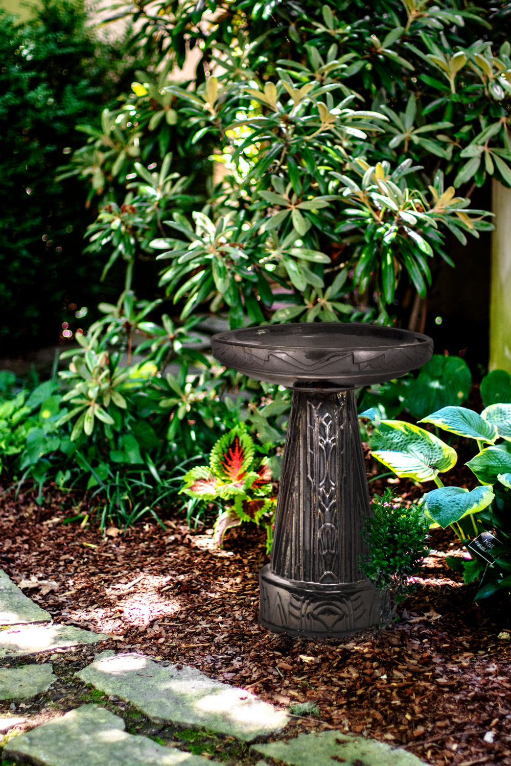 Art Deco Style reflective black birdbath in a garden setting with green foliage along a stone path