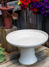 short sunflower design birdbath in white glaze next to a water pump