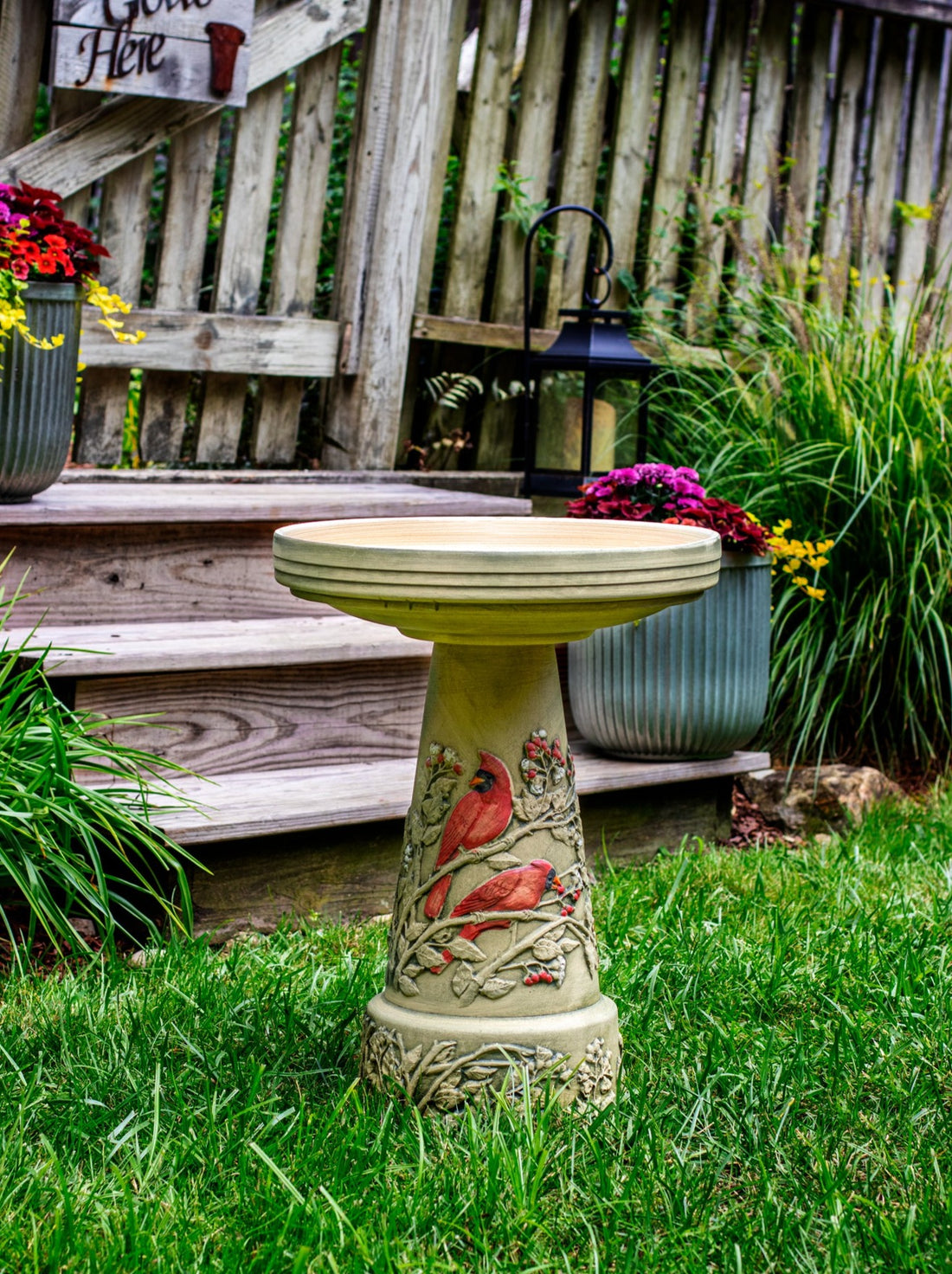 ceramic birdbath set with hand painted red cardinal design in landscaped garden area
