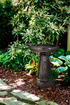 Art Deco Style reflective black birdbath in a garden setting with green foliage along a stone path