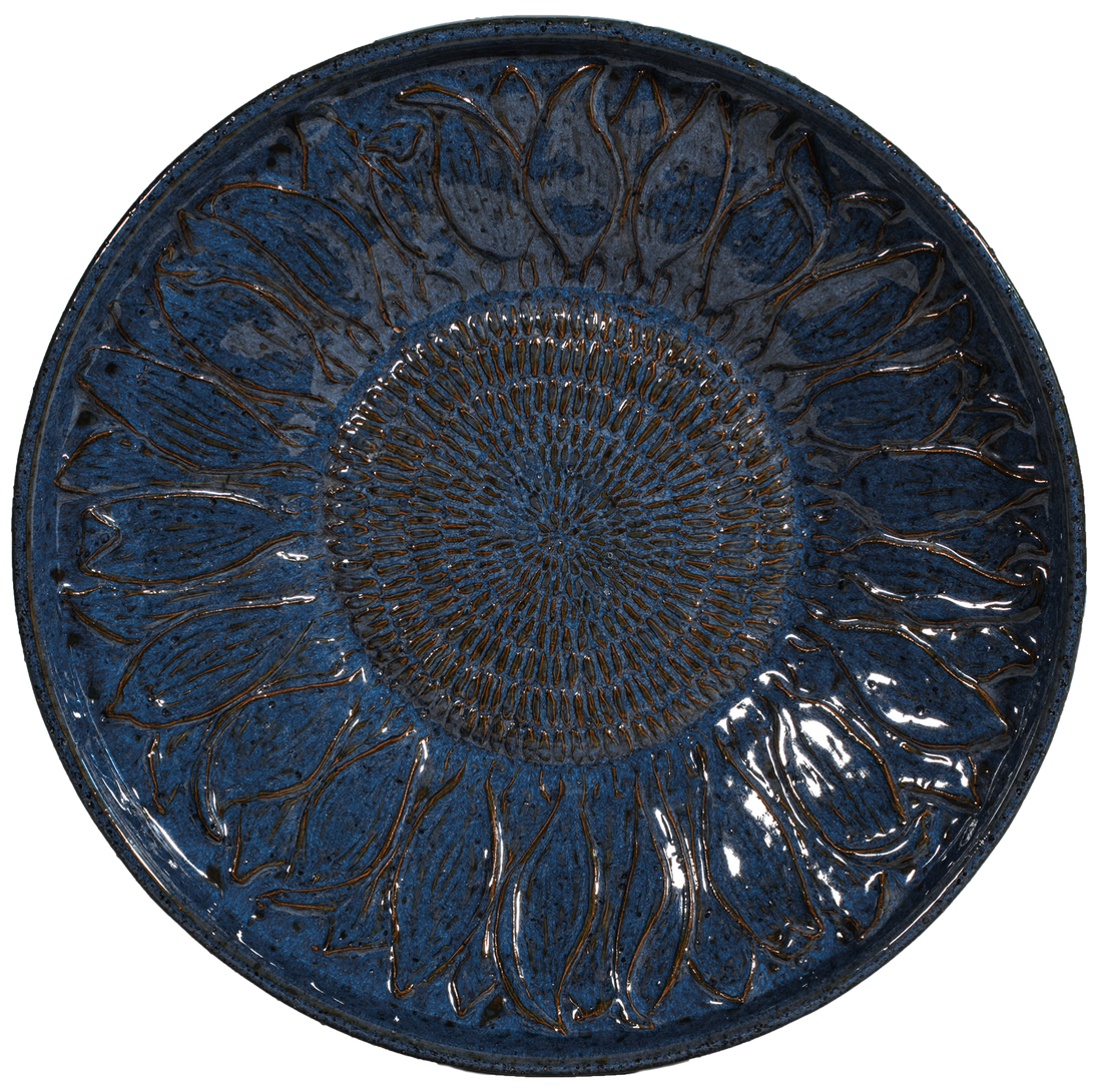 Round blue ceramic plate with sunflower design on a white background