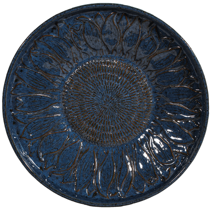 Round blue ceramic plate with sunflower design on a white background