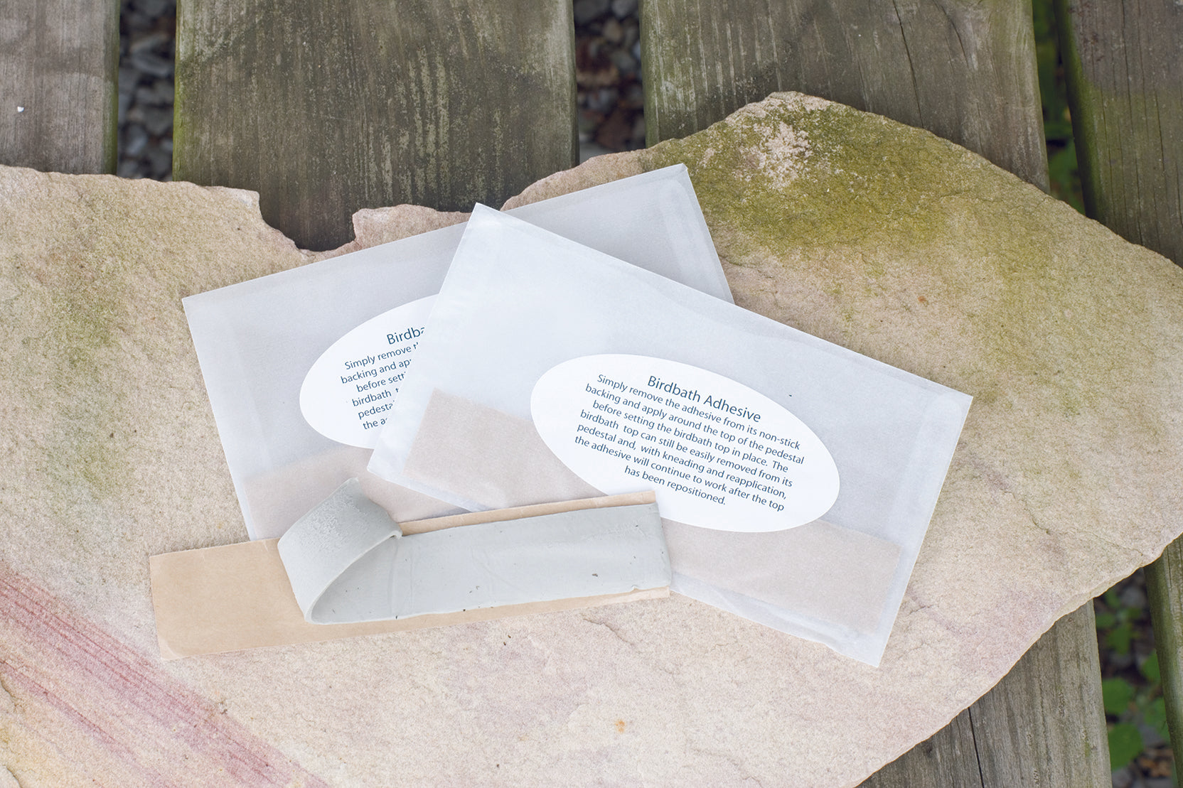 two strips of birdbath putty on a sheet of stone on a wooden table