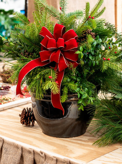 large glossy black ceramic planter in the shape of a bell with Christmas wreath arrangement