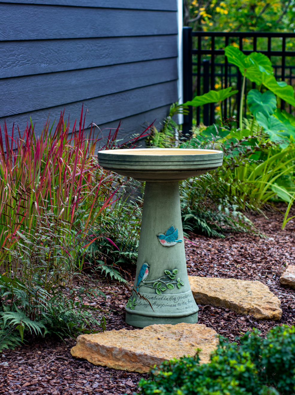 ceramic birdbath set with hand painted bluebird design and saying in landscaped garden area