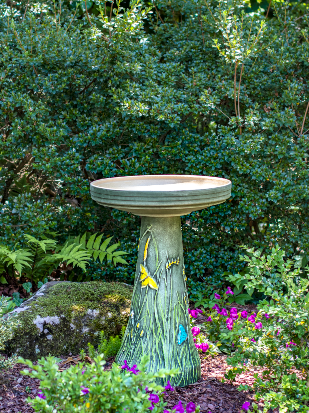 ceramic birdbath set with hand painted butterflies in landscaped garden area