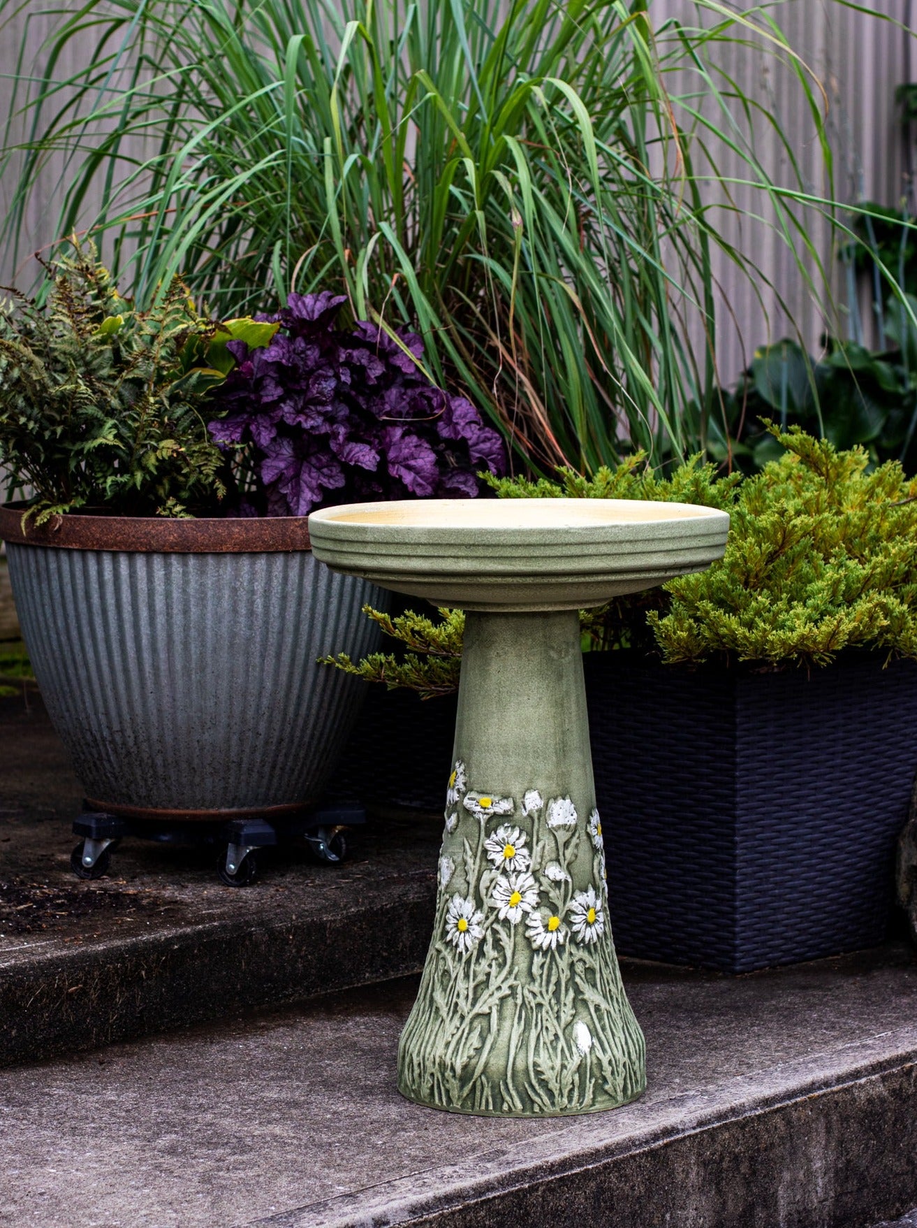 ceramic birdbath set with hand painted daisy flower design in landscaped garden area