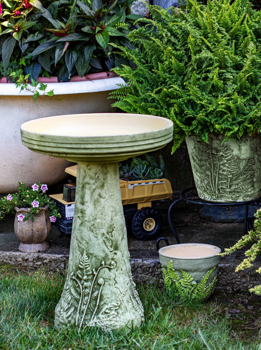 ceramic birdbath set with hand aged Fern design in landscaped garden area with fern planters