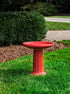 ceramic red birdbath with column design in a landscaped garden setting