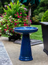 ceramic blue birdbath with simple modern smooth design in a landscaped garden setting