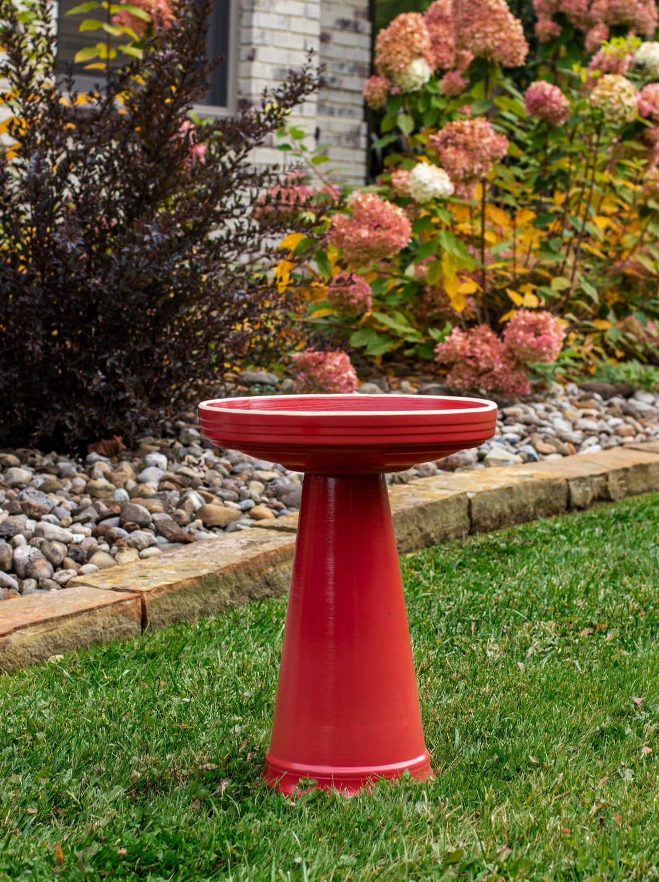 ceramic locking birdbath set in red glaze in a landscaped garden setting