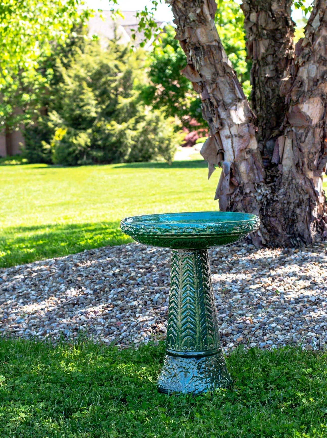 ceramic green birdbath set with birds flowers and a chevron design in a landscaped garden setting