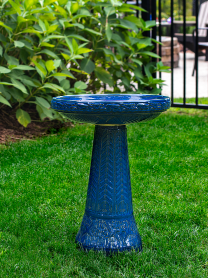 ceramic blue birdbath with birds and flowers design in a landscaped garden setting