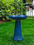 ceramic blue birdbath with birds and flowers design in a landscaped garden setting