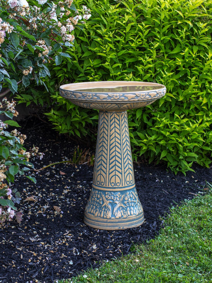 ceramic light blue birdbath set with birds flowers and a chevron design in a landscaped garden setting