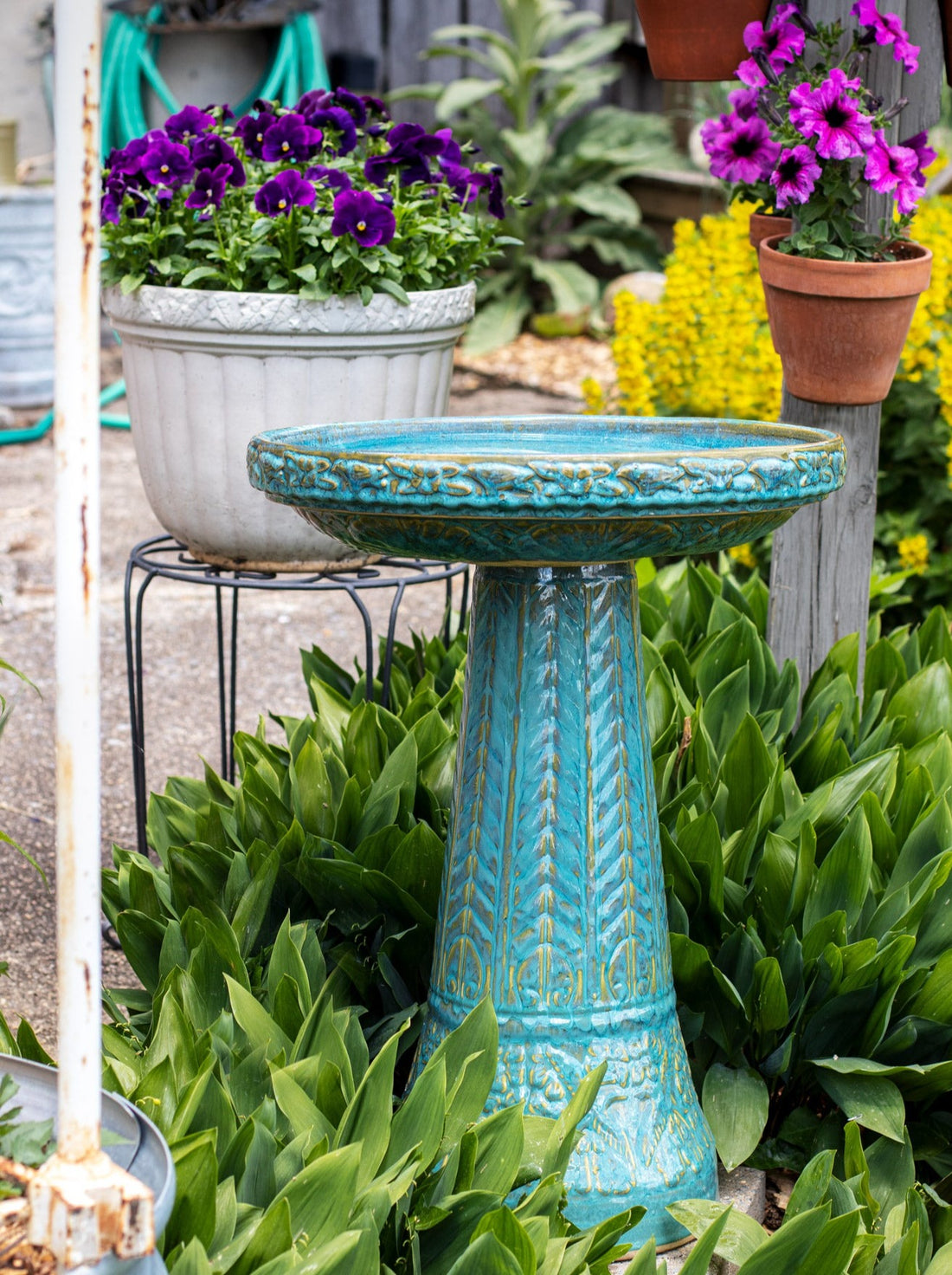 ceramic Turquoise birdbath set with birds flowers and a chevron design in a landscaped garden setting