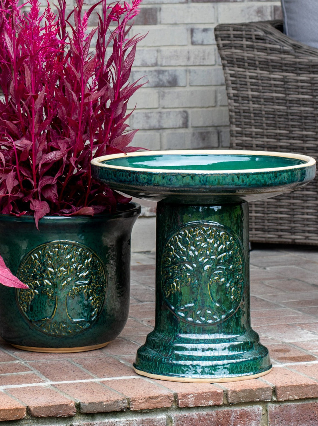 ceramic dark green birdbath set with Tree of Life motif on brick patio