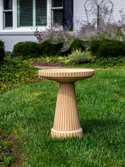 ceramic birdbath set in brown striped tan color in a landscaped garden setting